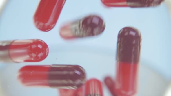 Red Capsules Of The Medication Is Falling Down Into The Camera