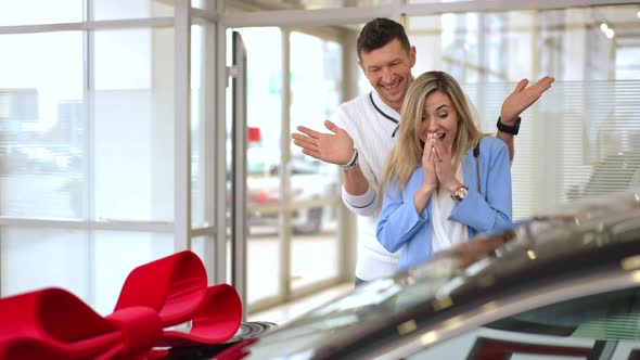 Loving Man Buying New Automobile for Woman in Car Dealership Surprising Partner alt