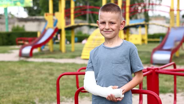 unhappy child with broken limb arm outdoors on playground background. school boy had accident 