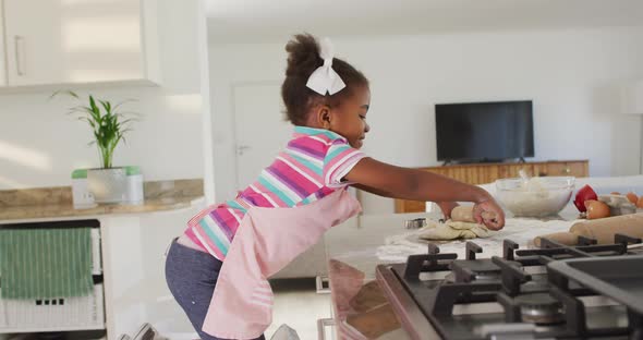 Happy african american girl rolling dough in kitchen alt