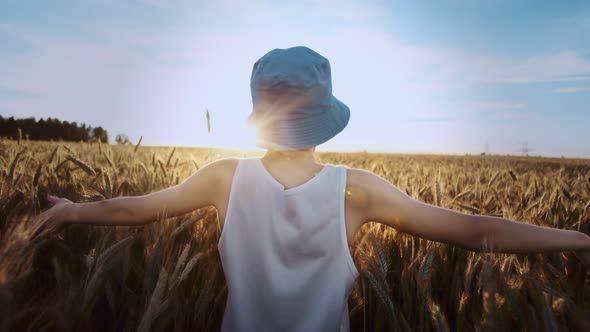 Funny Teen Boy in a Blue Hat Walks on a Golden Wheat Field on a Sunny Day Cinematic Shot alt