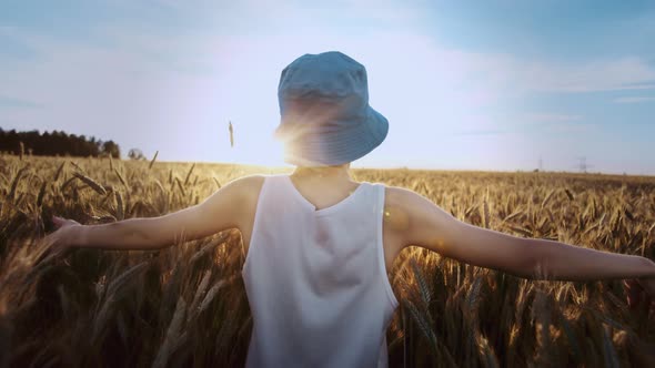 Funny Teen Boy in a Blue Hat Walks on a Golden Wheat Field on a Sunny Day Cinematic Shot