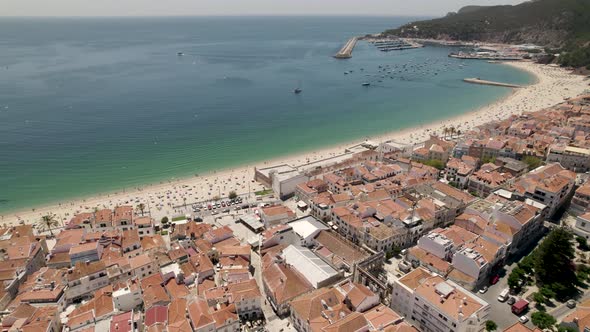 Seascape aerial view of Sesimbra beach full of tourists seen from town, Portugal alt