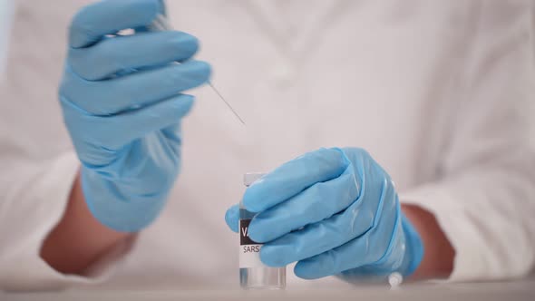 Close Up of Doctor Hands in Blue Protecting Gloves Fills the Vaccine From the Vial Into the Syringe