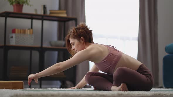 Adult Sporty Woman is Training Alone in Living Room Morning Workout in Apartment Practicing Yoga alt