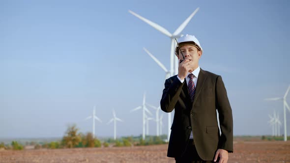 businessman is using Walkie Talkie to work at the wind power project