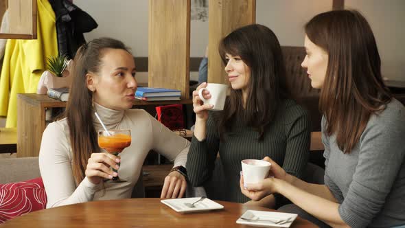 Three Girlfriends are Meeting in Cafe alt
