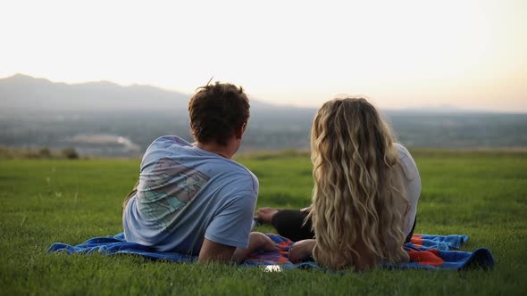 Shot of cute boyfriend and girlfriend laying on a blanket and having a picnic on the grass. alt