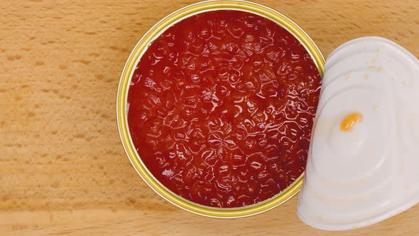 The chef opens a jar of red caviar. A man's hand opens a tin can of red salmon caviar. Concept