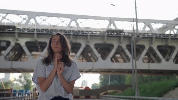 Anxious and Afraid Woman is Waiting Someone on Street in Outskirts at Summer Day alt