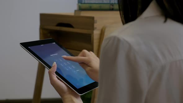 Young Attractive Caucasian Woman Holds a Tablet in Her Hands Enters the Password and Unlocks It alt
