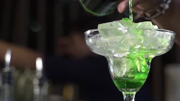 Green Liqueur Is Poured Into a Glass with Ice