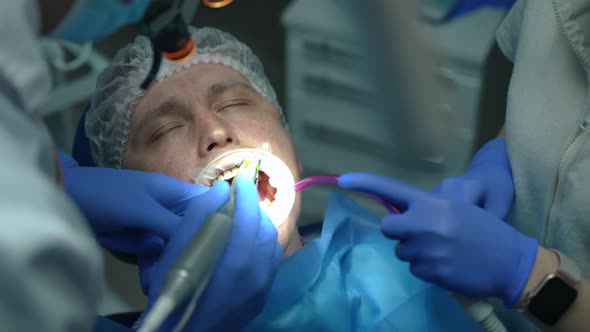 Closeup Portrait of Caucasian Patient in Dental Chair Closing Eyes As Doctor Drilling Ill Tooth and alt