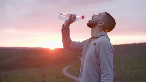 Runner Drinking Water After Workout in Field