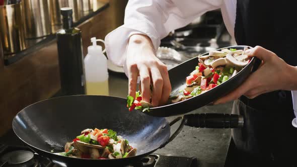 Chef adding vegetables on the pan alt