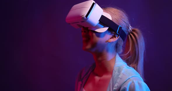 Young Asian woman playing metaverse virtual reality digital technology game with VR goggle. alt