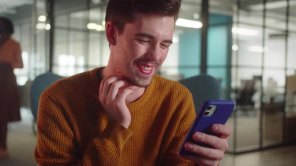 A Young Manstudent Sits on the Chair and Reads Humorous Posts on the Internet Close Up Slow Motion alt