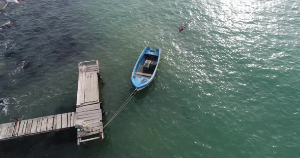 4k aerial video of lonely fishing boat and wooden pier in turquoise ocean, sea. alt