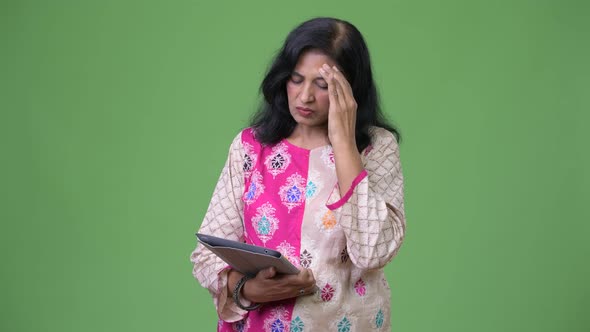 Mature Stressed Indian Woman Using Digital Tablet and Getting Bad News alt