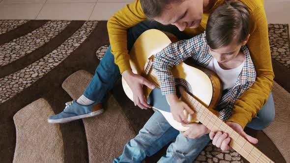 Child playing guitar and singing song with dad