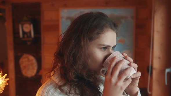 Portrait of Young Caucasian Woman Drinking Coffee and Looking Through the Window alt