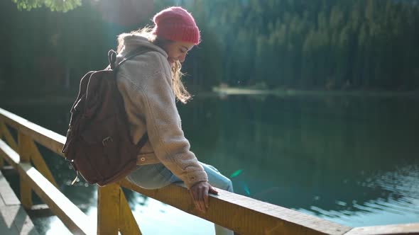 Slow Motion Inspired Joyful Woman Hiker Sits on Wooden Pier at Beautiful Mountain Lake with alt
