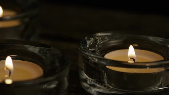 Tea candles with flaming wicks on a wooden background - CANDLES 011 alt