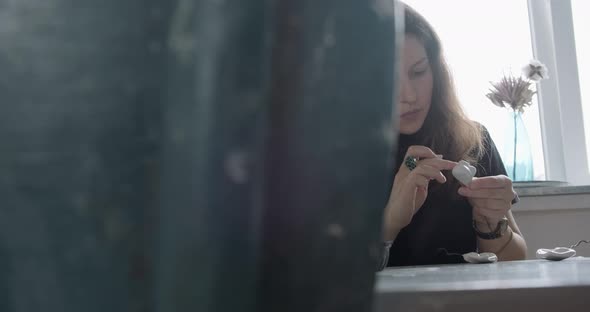Woman Making Doll Ceramic Part. Female Sitting and Creating Ear for Doll at Home at Table. Pottery alt