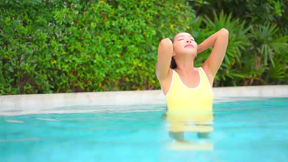 Young asian woman enjoy around outdoor swimming pool for leisure alt