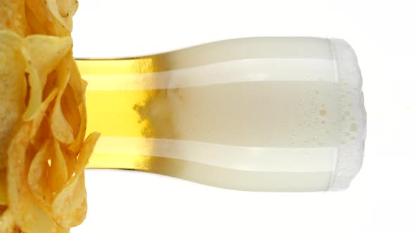 Pouring beer in glass, white background. Beer and chips. Vertical video alt
