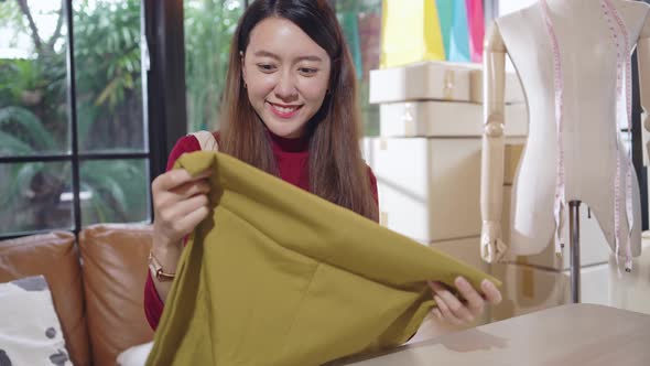 Asian female small business shop owner checking clothes quality before shipping