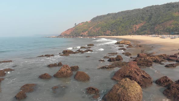 Arambol rocky idyllic shoreline in North Goa, India - Aerial low angle fly-over shot alt