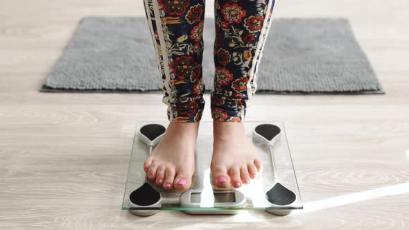 Woman Measuring Her Body Weight by Standing on Electronic Bathroom Scale Indoors
