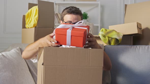 Man Opens Received Parcel in a Big Carton Box. Man Takes From a Big Carton Box a Present. alt
