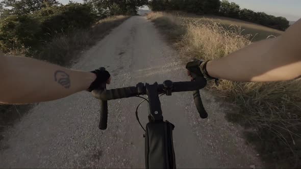 Biker riding downhill on dust road, Marche, Italy alt