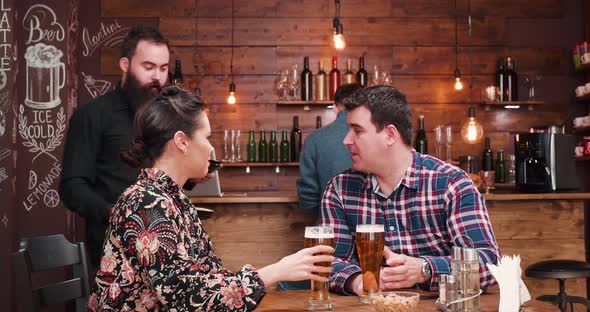 Bearded Waiter Bringing Pizza To a Beautiful Couple at the Table alt