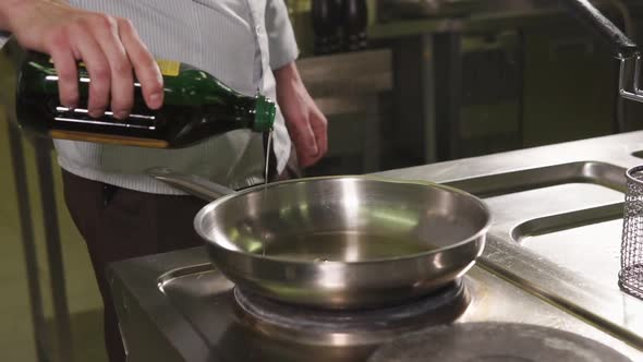 Male Cook Adding Oil in a Pan alt