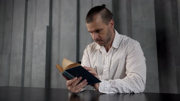 A Man in a Dark Modern Room is Reading an Old Vintage Book