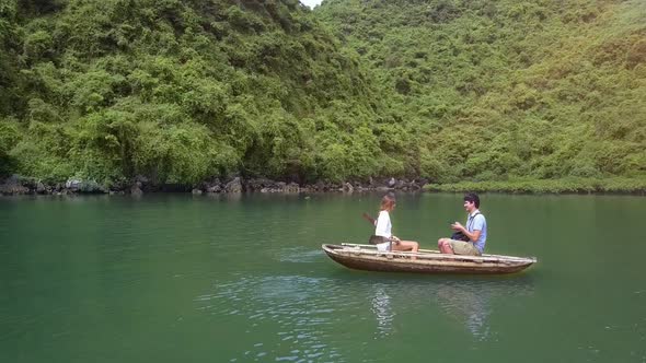 Drone Shows Girl and Man Rowing on Boat on Lake By Ha Long Bay alt