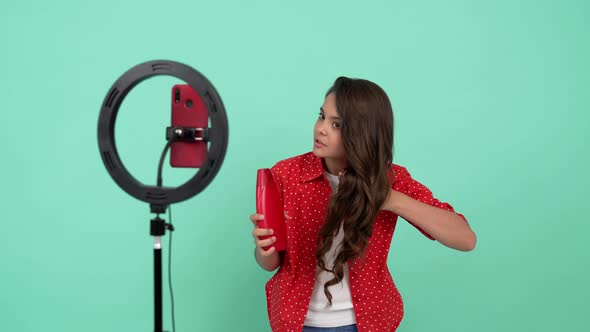 Happy Kid Beauty Blogger Has Long Curly Hair Presenting Cosmetic Product for Teen Hair Shampoo alt