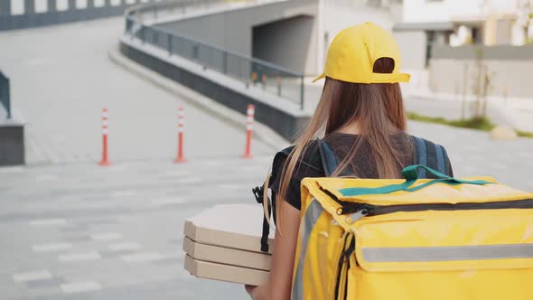 Caucasian Young Pretty Woman Delivery Worker Cap and Medical Mask Walking the alt