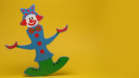 Funny wooden clown on yellow background
