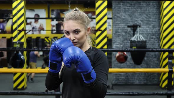 A Young Athletic Boxer Girl Looks Into the Camera and Prepares for a Punch