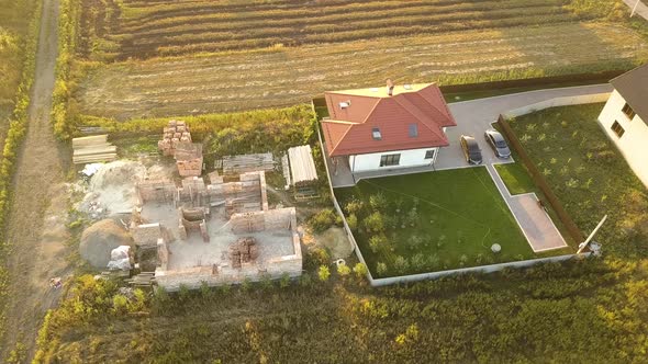 Top down aerial view of two private houses, one under construction with wooden roofing frame  alt