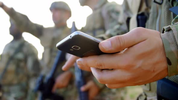 Mid section of caucasian military soldier using mobile phone during military training 4k alt