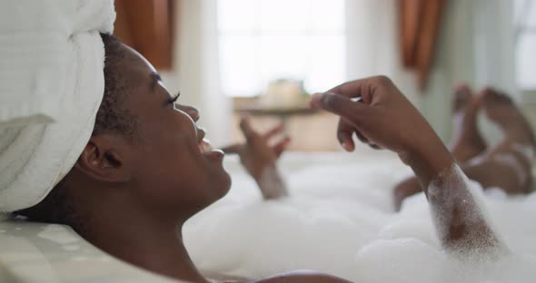 Profile of african american attractive woman relaxing in bath and singing in bathroom alt