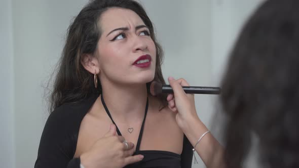 Back View Of A Girl Putting Facial Powder With Big Brush On Her Friend's Neck alt