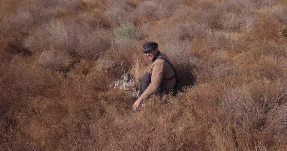 a man in the field training with his falcon that caught a pigeon alt