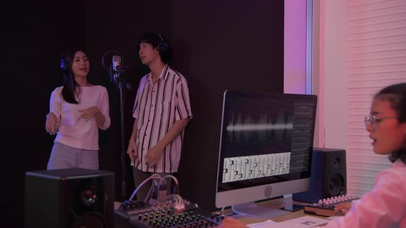 Audio recording concept. Asian male and female couple singing in the studio. 4k Resolution. alt