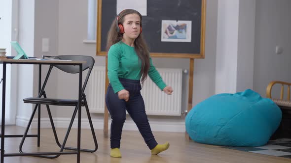 Funny Dance of Positive Smiling Caucasian Little Person in Headphones Indoors alt